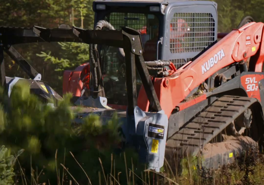 Kubota track loader with a forestry mulcher pushing into a young pine tree